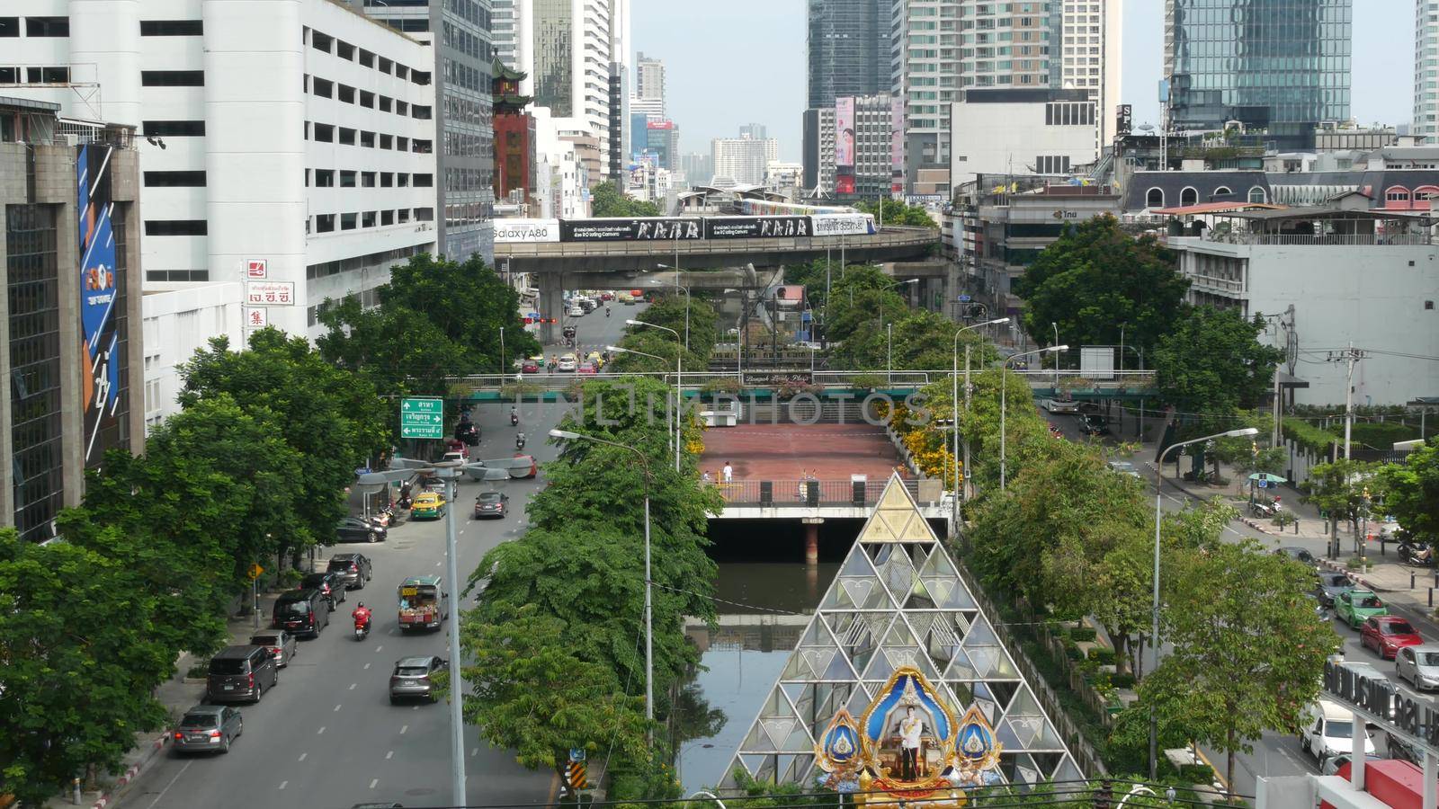 BANGKOK, THAILAND - 13 JULY, 2019: Traffic on modern city street. Contemporary train riding on railroad bridge over road with cars in center of capital