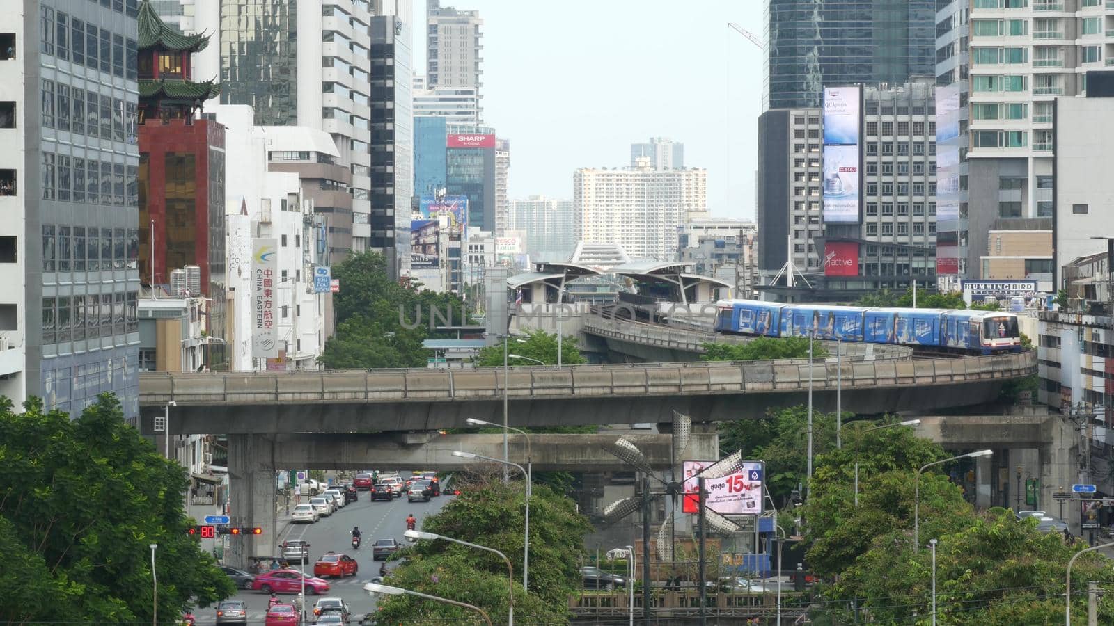 BANGKOK, THAILAND - 13 JULY, 2019: Traffic on modern city street. Contemporary train riding on railroad bridge over road with cars in center of capital