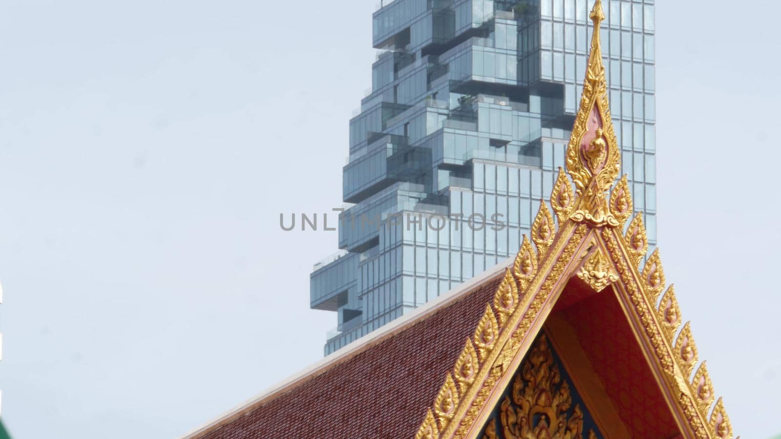 BANGKOK, THAILAND - 13 JULY, 2019: Conceptual contrast of oriental old traditional ancient temple and modern new futuristic Mahanakhon skyscraper. Classic buddhist wat compared to urban cityscape