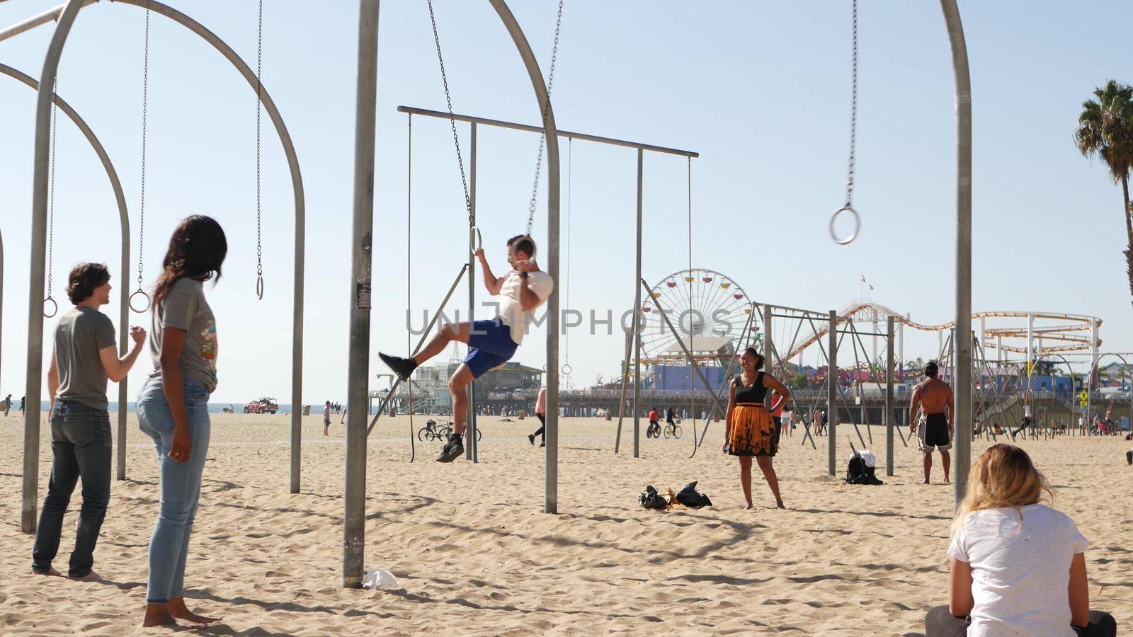 SANTA MONICA, LOS ANGELES CA USA - 28 OCT 2019: California summertime pacific ocean beach aesthetic, young people training and having fun on sports ground. Muscle beach and amusement park on pier by DogoraSun