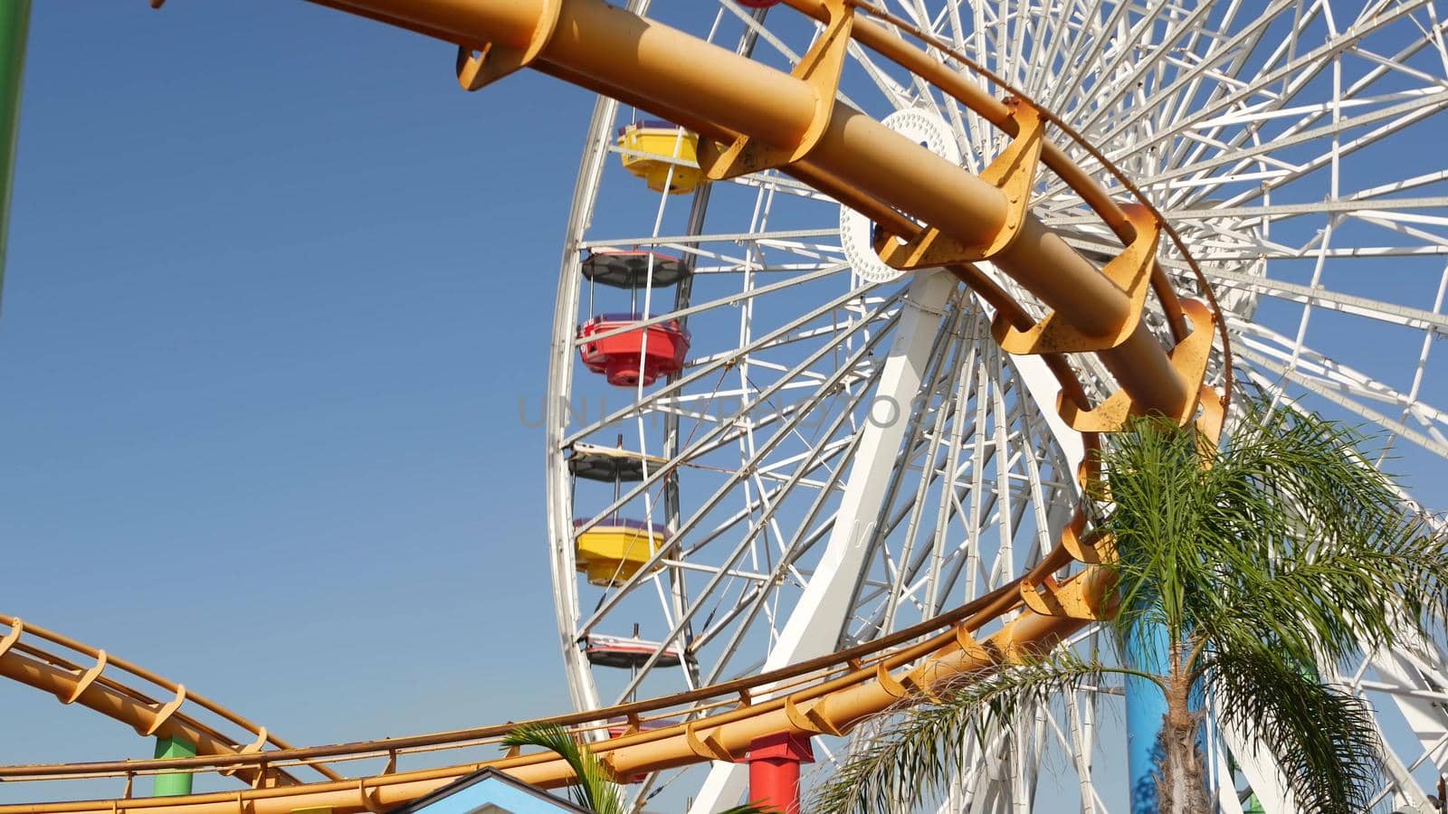 SANTA MONICA, LOS ANGELES, USA - 28 OCT 2019: Iconic colorful retro ferris wheel, roller coaster in amusement park. Famous classic california summertime symbol, pier of pacific ocean beach resort by DogoraSun