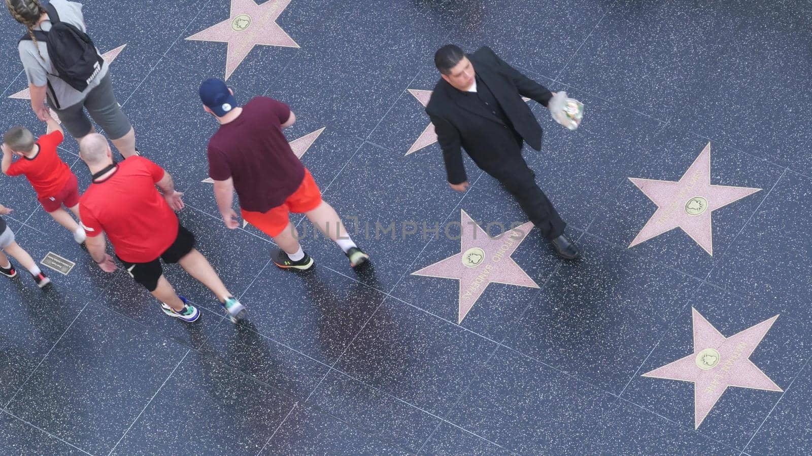 LOS ANGELES, CALIFORNIA, USA - 7 NOV 2019: Walk of fame promenade on Hollywood boulevard in LA. Pedastrians walking near celebrity stars on asphalt. Walkway floor near Dolby and TCL Chinese Theatre by DogoraSun