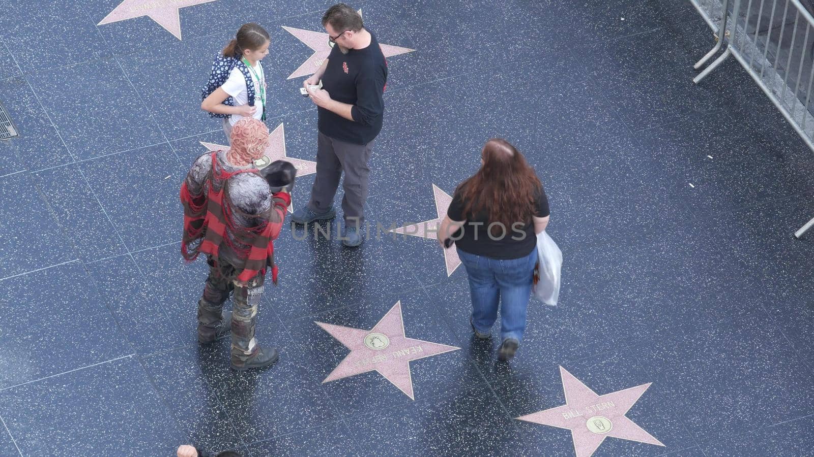 LOS ANGELES, CALIFORNIA, USA - 7 NOV 2019: Walk of fame promenade on Hollywood boulevard in LA. Pedastrians walking near celebrity stars on asphalt. Walkway floor near Dolby and TCL Chinese Theatre by DogoraSun