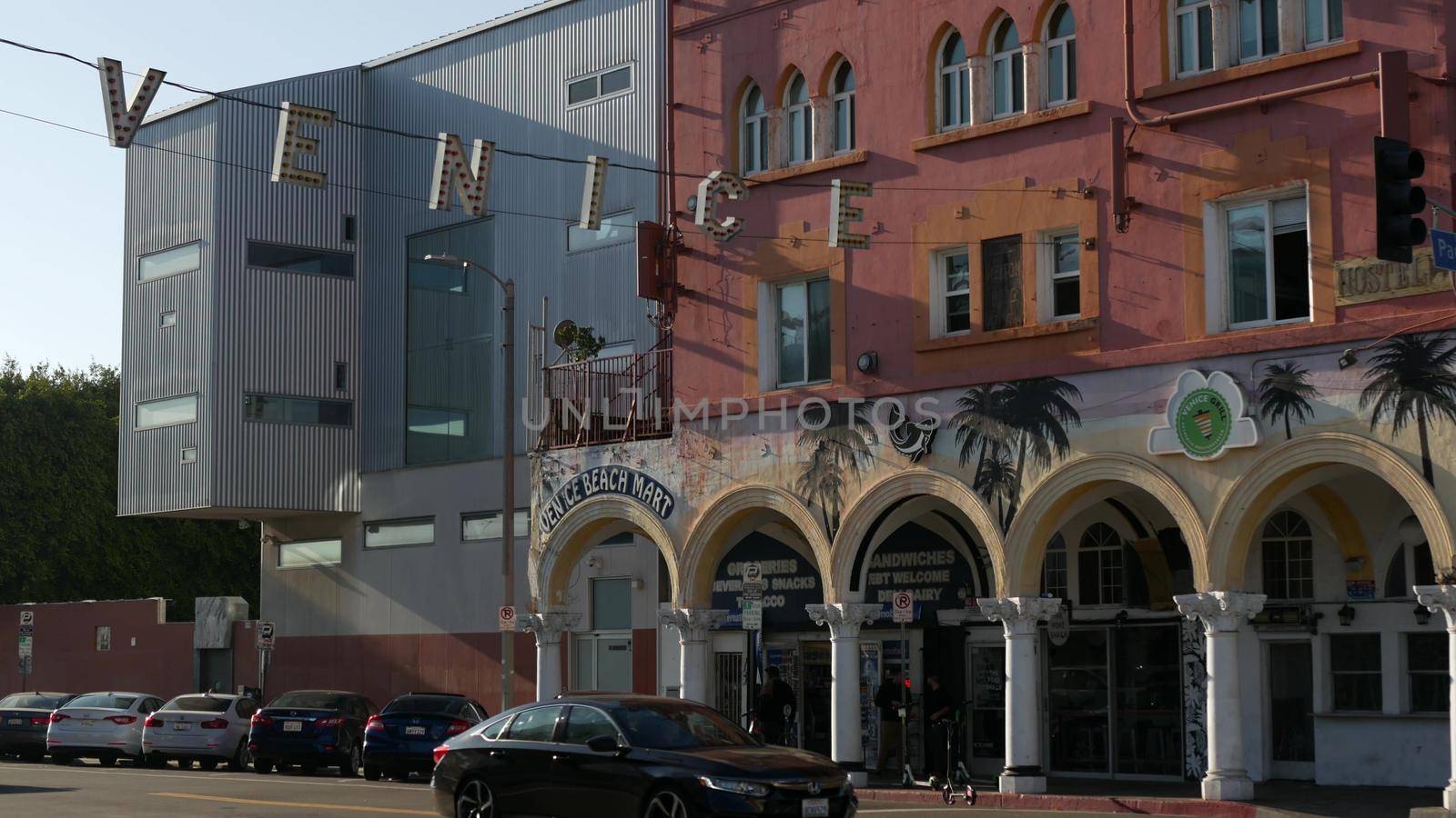 LOS ANGELES CA USA - 16 NOV 2019: California summertime Venice beach aesthetic. Iconic retro sign hanging on street. Famous symbol and travel destination. Letters over the road with cars and people.