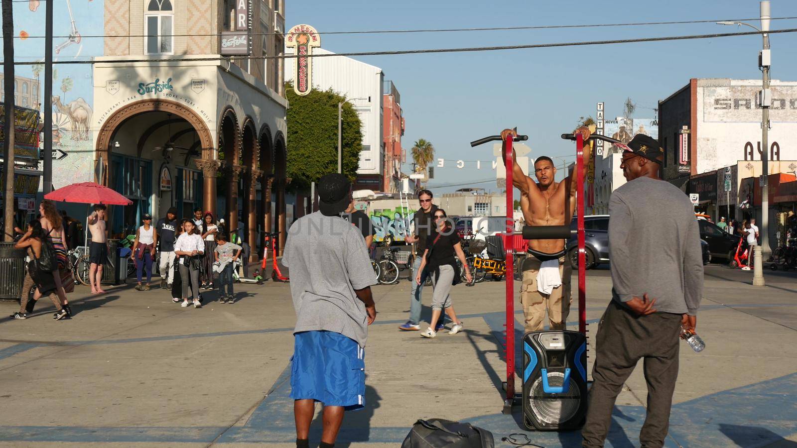 LOS ANGELES CA USA - 16 NOV 2019: California summertime Venice beach aesthetic. African american street performer training on walkway. Black ethnicity strong bodybuilder, men having fun on promenade.