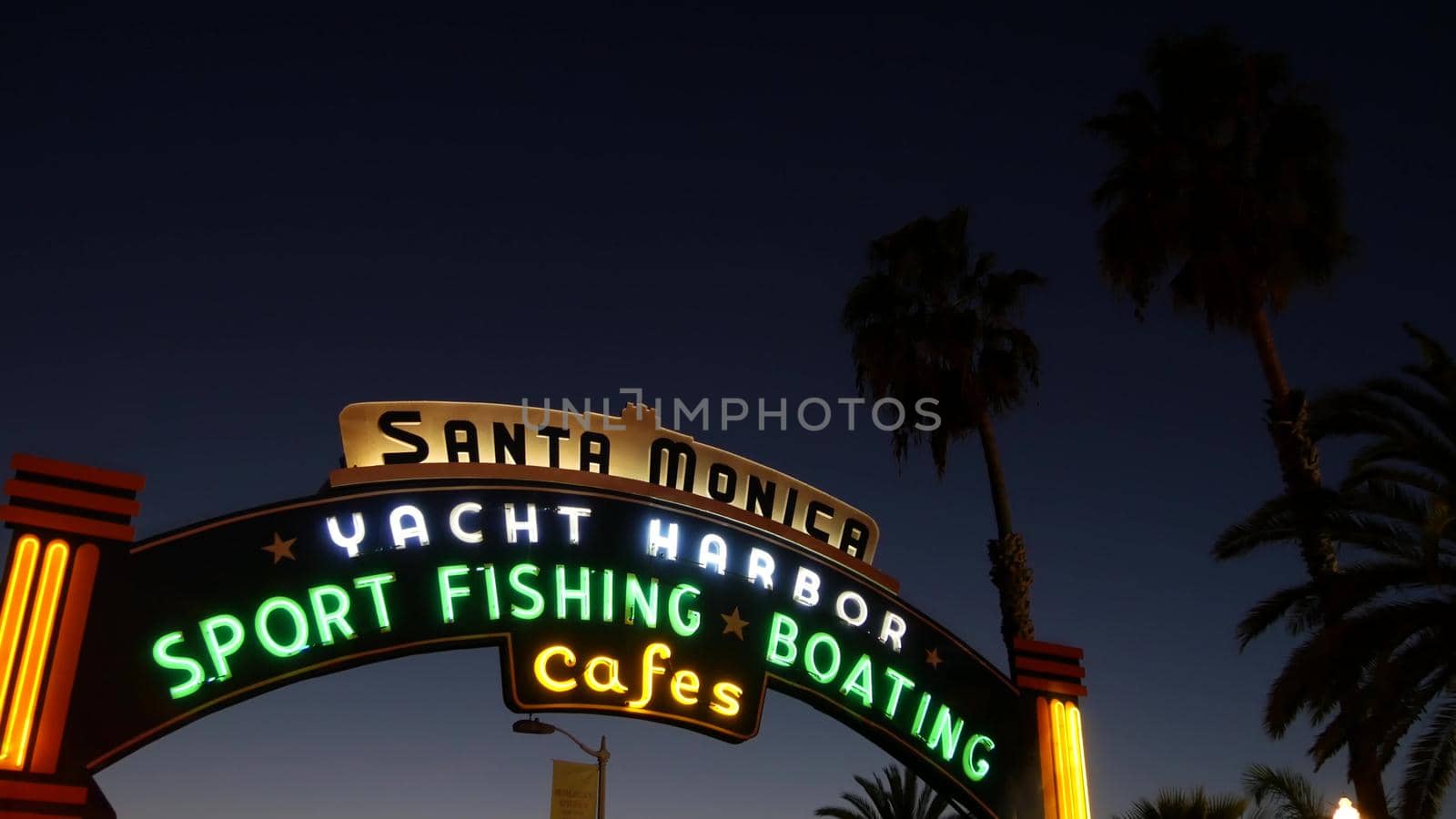 SANTA MONICA, LOS ANGELES CA USA - 19 DEC 2019: Summertime iconic vintage symbol. Classic illuminated retro sign on pier. California summertime aesthetic. Glowing lettering on old-fashioned signboard.