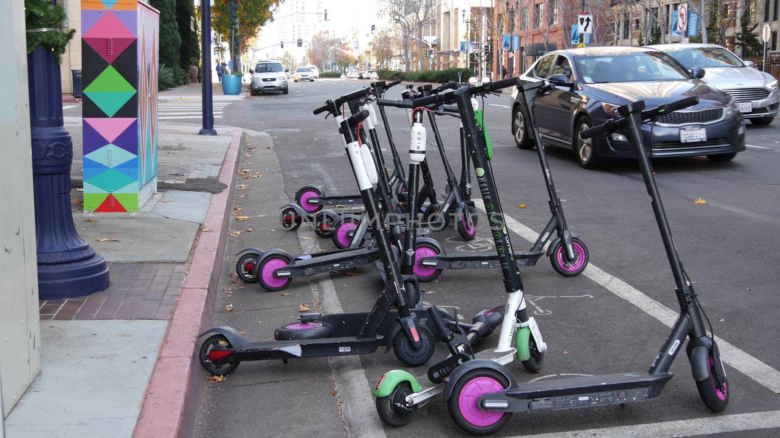 SAN DIEGO, CALIFORNIA USA - 4 JAN 2020: Row of ride sharing electric scooters parked on street in Gaslamp Quarter. Rental dockless public bikes, eco transport in city. Rent kick cycle with mobile app by DogoraSun