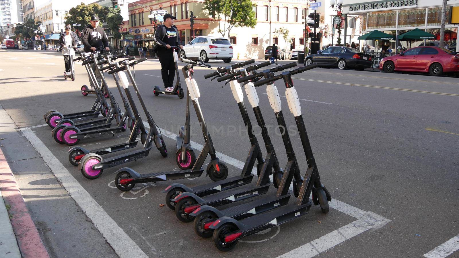 SAN DIEGO, CALIFORNIA USA - 4 JAN 2020: Row of ride sharing electric scooters parked on street in Gaslamp Quarter. Rental dockless public bikes, eco transport in city. Rent kick cycle with mobile app.