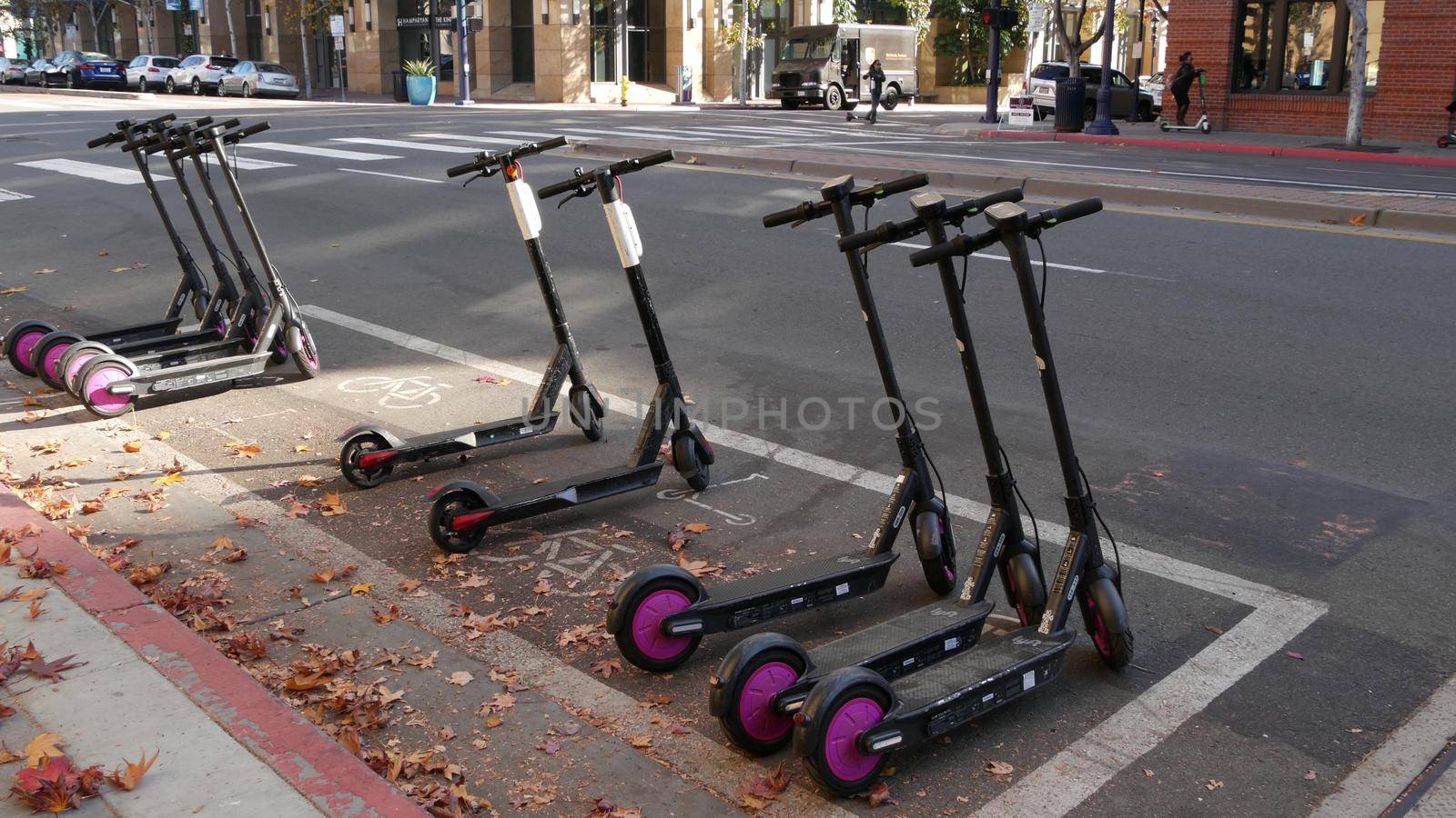 SAN DIEGO, CALIFORNIA USA - 4 JAN 2020: Row of ride sharing electric scooters parked on street in Gaslamp Quarter. Rental dockless public bikes, eco transport in city. Rent kick cycle with mobile app by DogoraSun