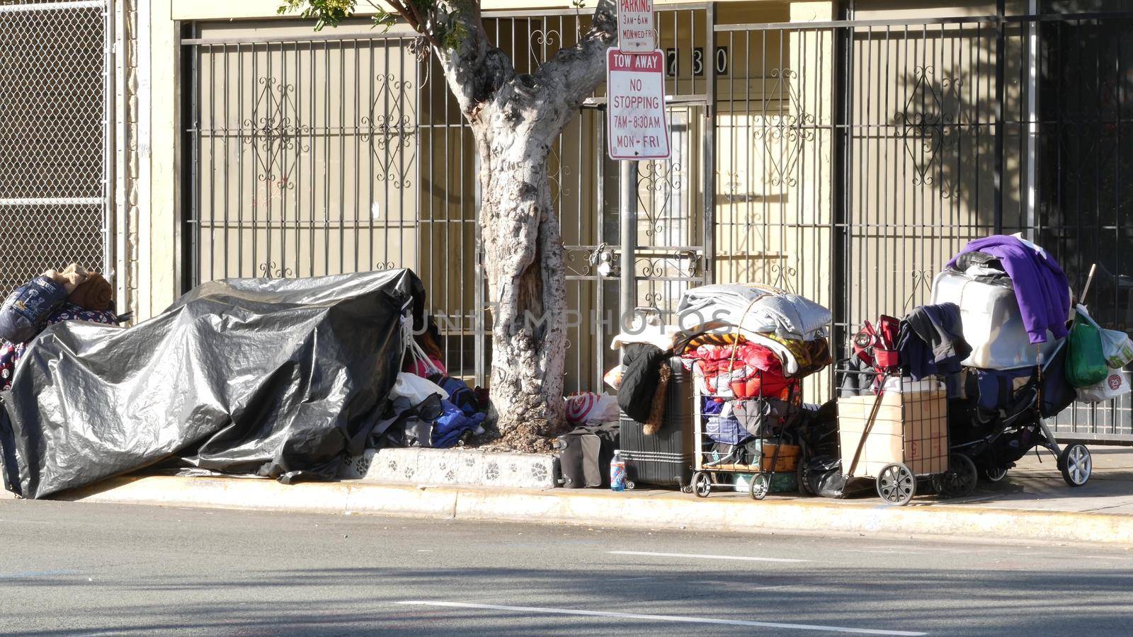 SAN DIEGO, CALIFORNIA USA - 4 JAN 2020: Stuff of homeless street people on walkway, truck on roadside. Begging problem in downtown of city near Los Angeles. Jobless beggars live on pavements.