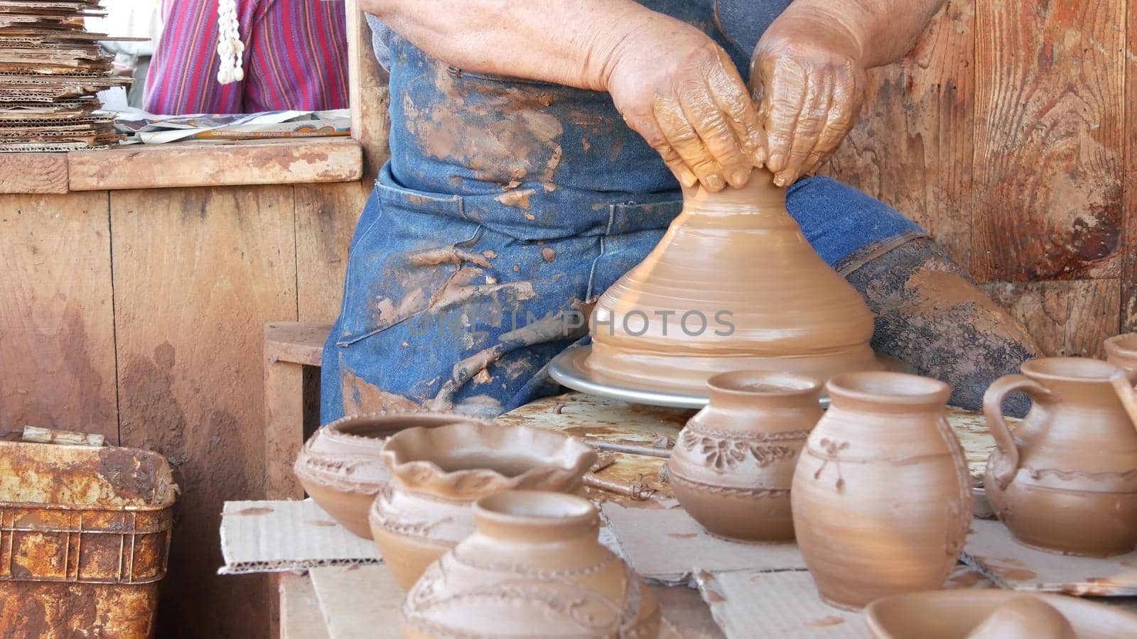 SAN DIEGO, CALIFORNIA USA - 5 JAN 2020: Potter working in mexican Oldtown, raw clay on pottery wheel. Man's hands, ceramist in process of modeling handcrafted clayware. Craftsman creating ceramic by DogoraSun