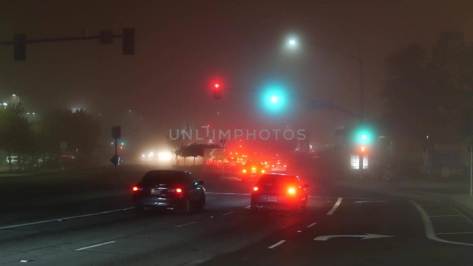 VISTA, CALIFORNIA USA - 24 JAN 2020: Marine layer, dense fog on driveway crossroad at night. June gloom, misty nebulous bad weather. Dangerous low visibility on road intersection. Car traffic safety by DogoraSun