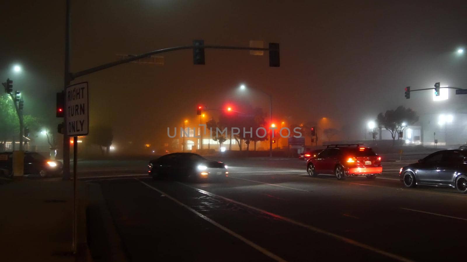 VISTA, CALIFORNIA USA - 24 JAN 2020: Marine layer, dense fog on driveway crossroad at night. June gloom, misty nebulous bad weather. Dangerous low visibility on road intersection. Car traffic safety.
