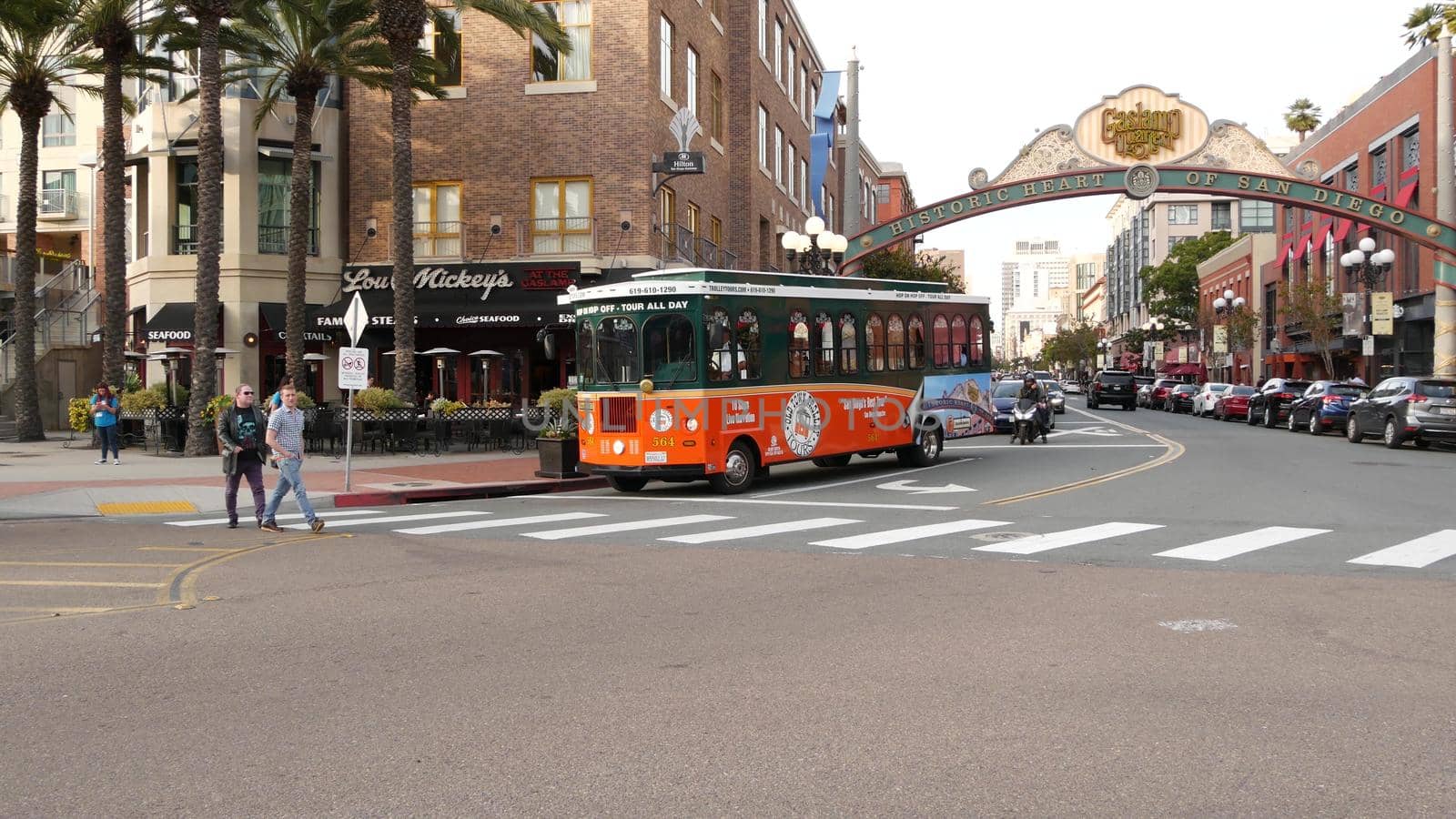 SAN DIEGO, CALIFORNIA USA - 30 JAN 2020: Gaslamp Quarter historic entrance arch sign on 5th avenue. Orange iconic retro trolley, hop-on hop-off bus and tourist landmark, Old Town Sightseeing Tour by DogoraSun