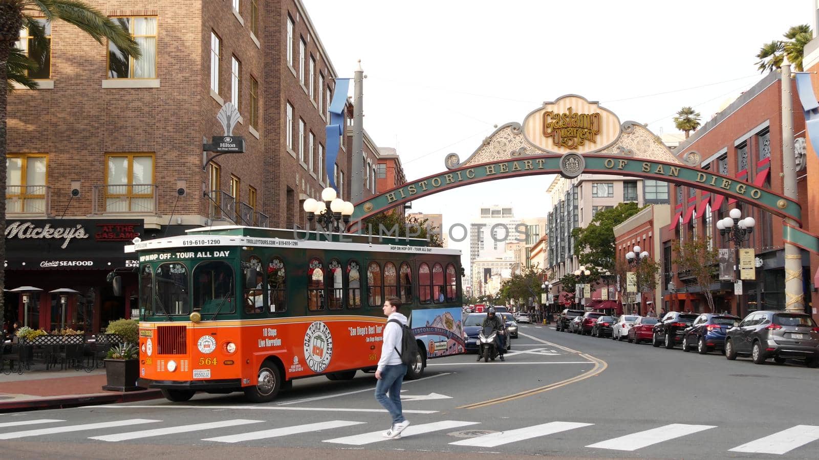 SAN DIEGO, CALIFORNIA USA - 30 JAN 2020: Gaslamp Quarter historic entrance arch sign on 5th avenue. Orange iconic retro trolley, hop-on hop-off bus and tourist landmark, Old Town Sightseeing Tour.