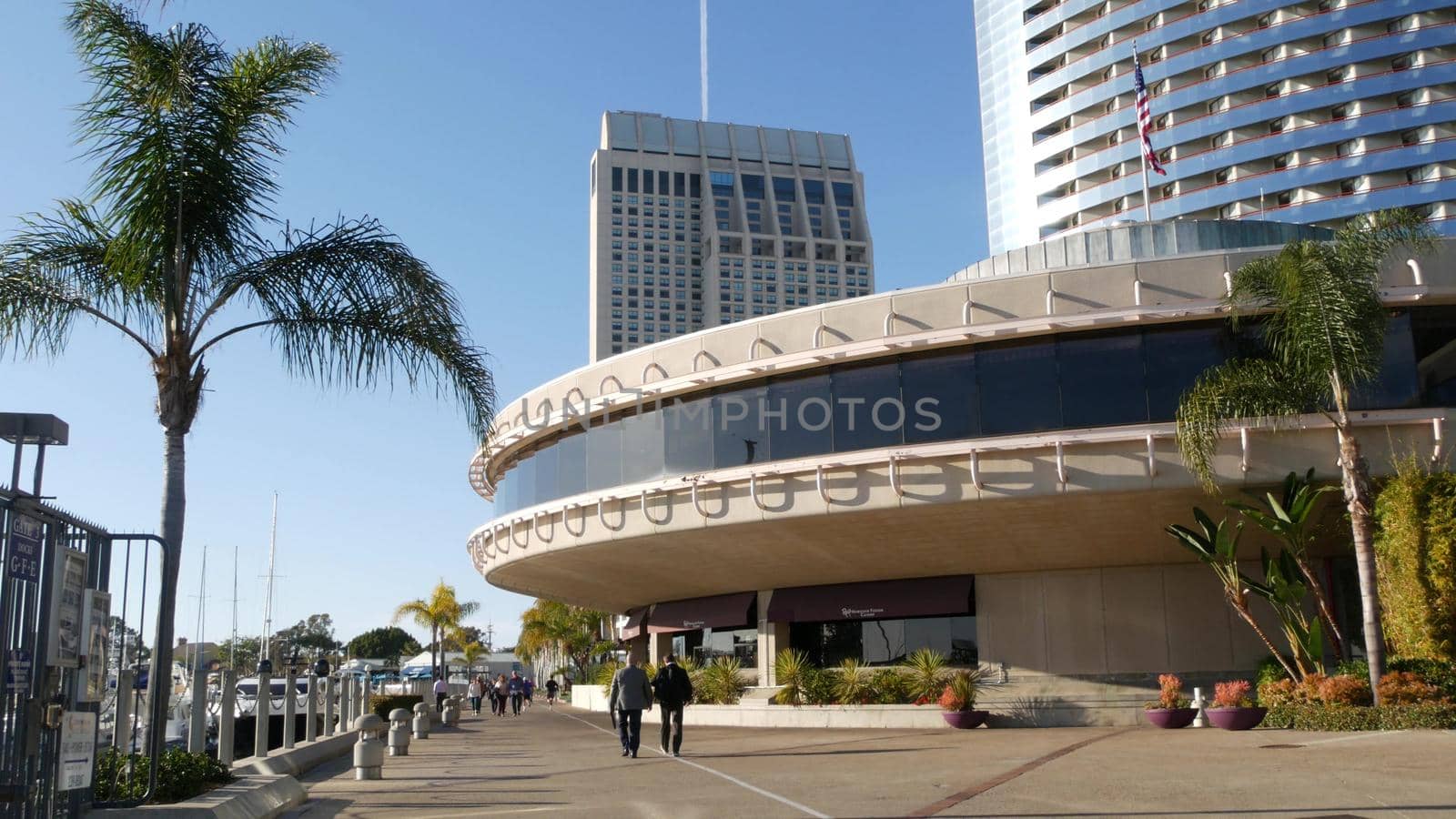 SAN DIEGO, CALIFORNIA USA - 13 FEB 2020: Pedestrians and highrise buildings in city downtown. Street life of american metropolis. Urban street and citizens walking on walkway. Embarcadero marina park.