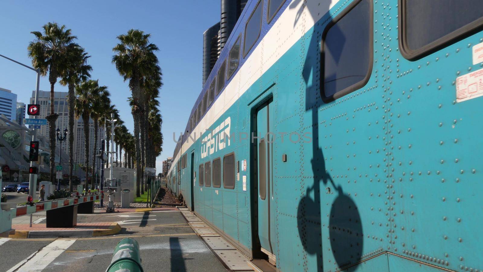 SAN DIEGO, CALIFORNIA USA - 13 FEB 2020: Coaster Commuter and palms, public rail transportation in America. Express passenger railway train, railroad nctd transport near Santa Fe station and Gaslamp.