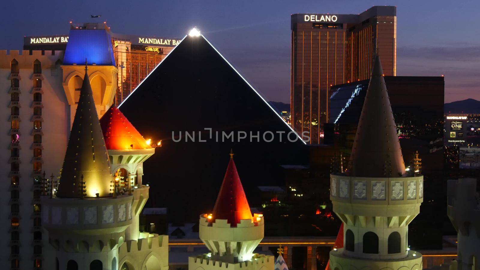 LAS VEGAS, NEVADA USA - 4 MAR 2020: Excalibur castle and Luxor pyramid casino uncommon aerial view. Plane flying from McCarran airport. Mandalay Bay and Delano hotel in american gambling sin city by DogoraSun