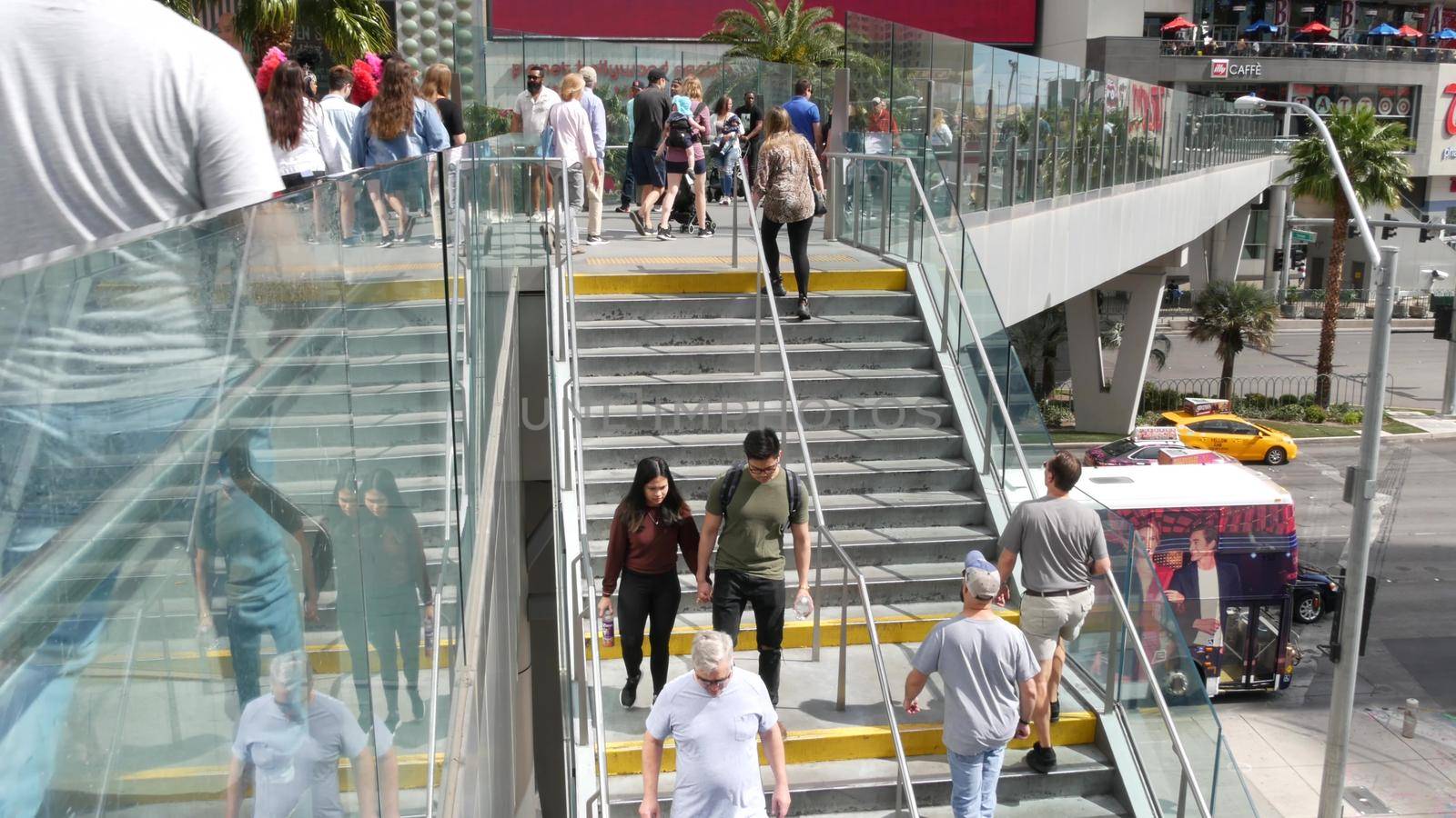 LAS VEGAS, NEVADA USA - 7 MAR 2020: People on pedestrian walkway. Multicultural men and women walking on city promenade. Crowd of citizens on sidewalk. Diversity of multiracial faces in metropolis by DogoraSun