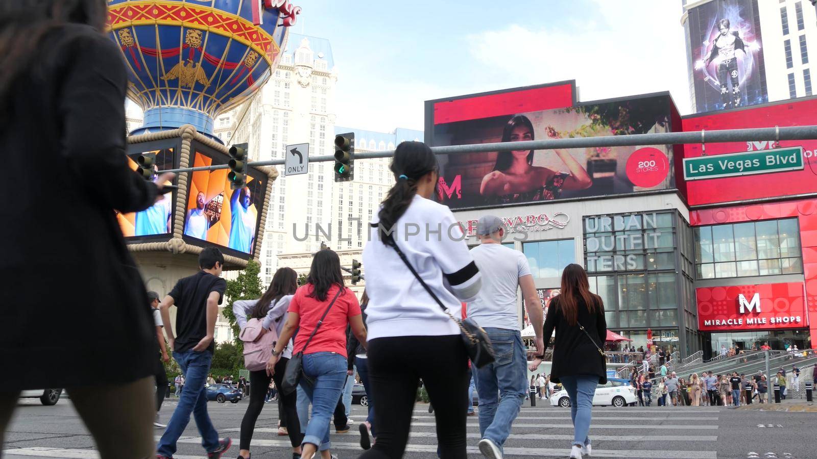 LAS VEGAS, NEVADA USA - 7 MAR 2020: People on pedestrian walkway. Multicultural men and women walking on city promenade. Crowd of citizens on sidewalk. Diversity of multiracial faces in metropolis by DogoraSun