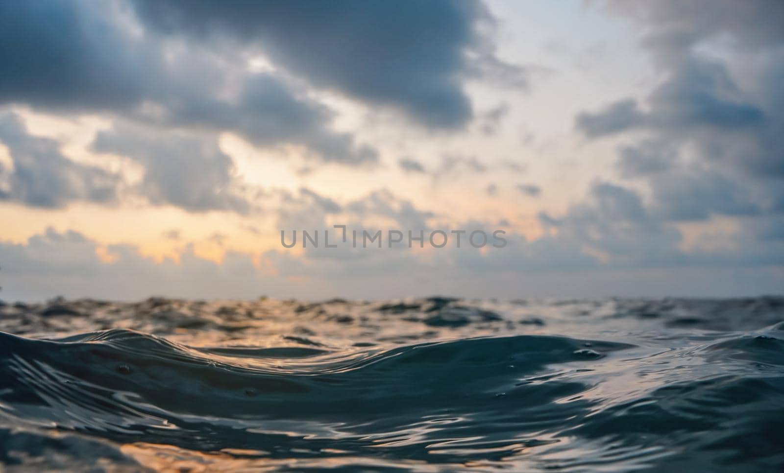 Sea surface, abstract closeup low angle view from swimming person point of view, morning overcast sky background.