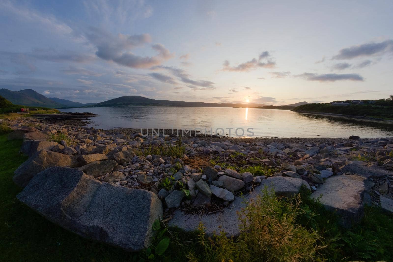 A rocky boulder sea shore at sunset. Looking west near East Suisnish on the Isle of Raasay, isle of skye in the distance. A fish eye perspective.