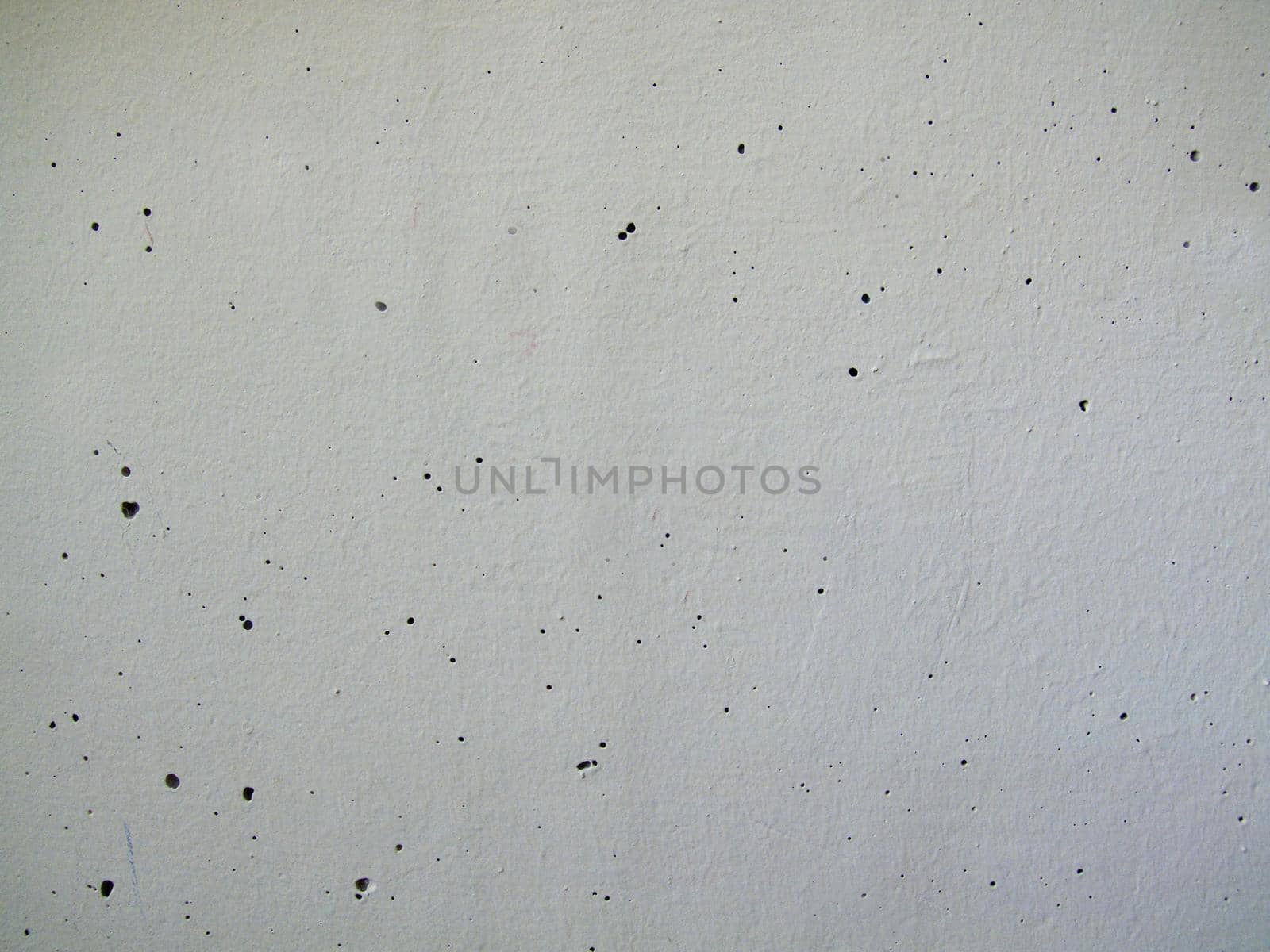 Close-up of a painted white concrete wall with holes in the surface.Texture or background