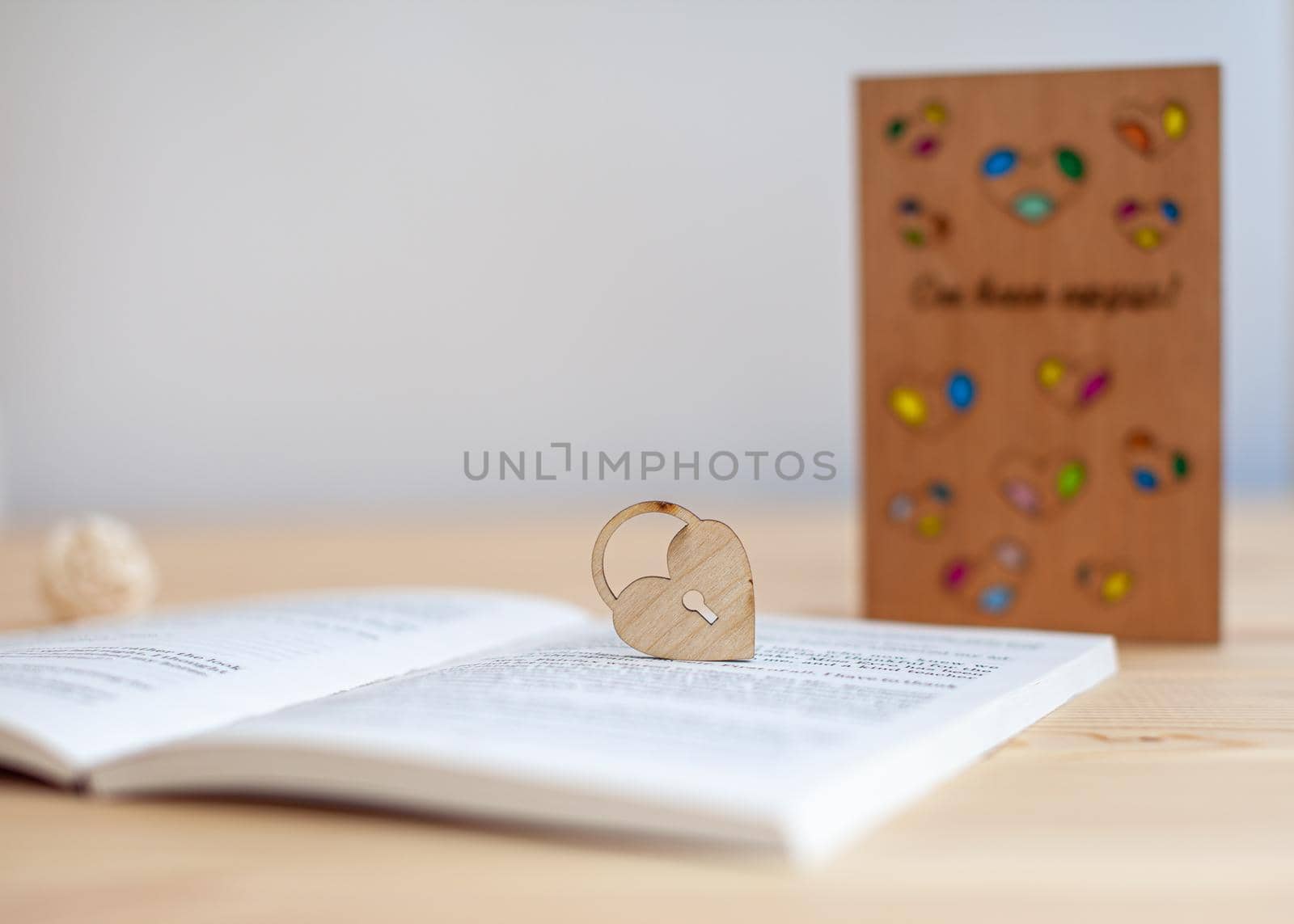 A wooden heart with a keyhole rests on an open book. There is a place for the text.