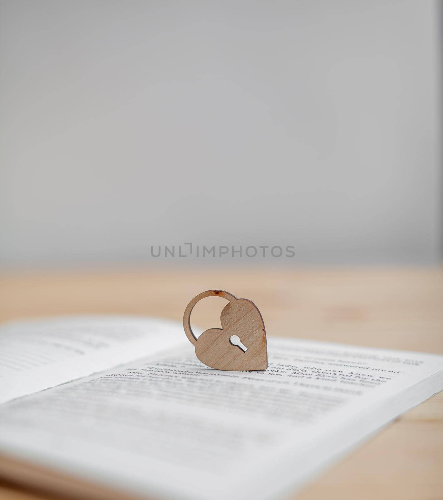 A wooden heart with a keyhole rests on an open book. There is a place for the text.