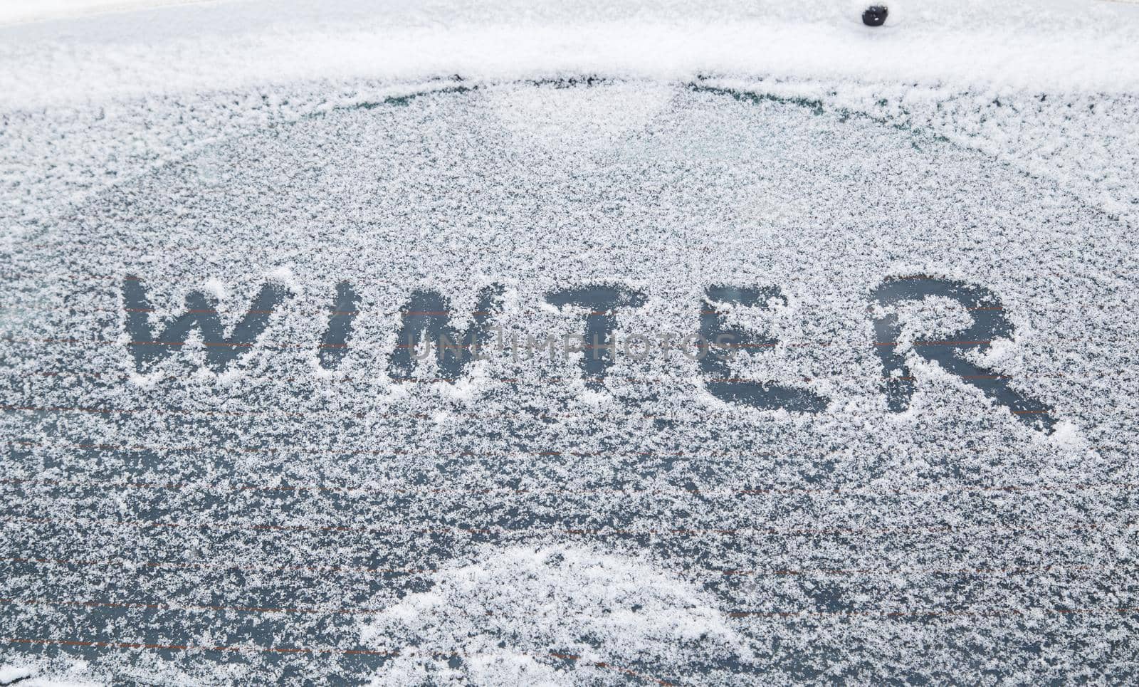 word winter handwritten on snowy car window at winter morning light by z1b