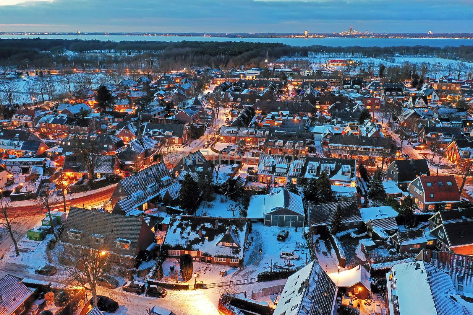 Aerial from a snowy village Huizen in winter in the Netherlands at twilight