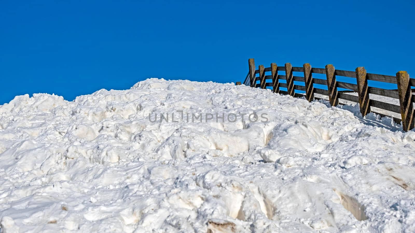 Fence, lots of snow and a blue sky