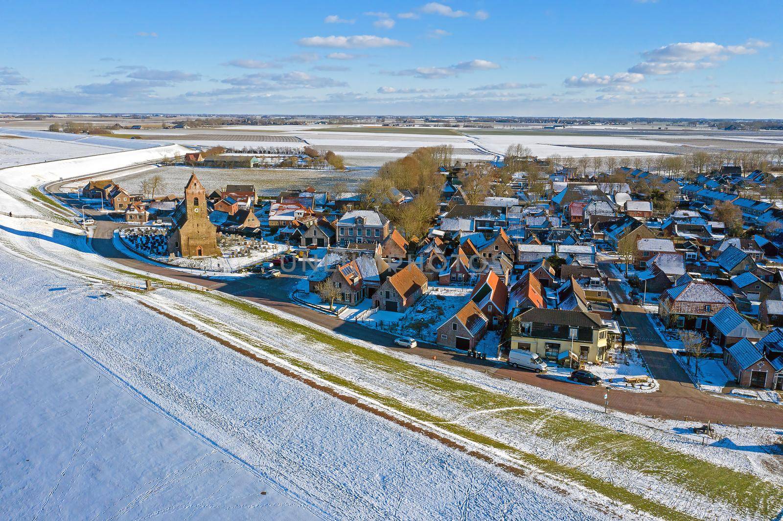 Aerial from snowy village Wierum in Friesland at a frozen Waddensea in the Netherlands in winter