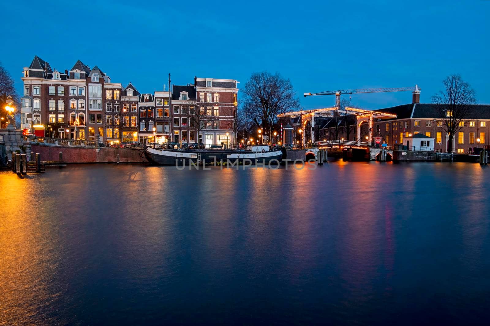 City scenic from Amsterdam by night at the river Amstel in the Netherlands