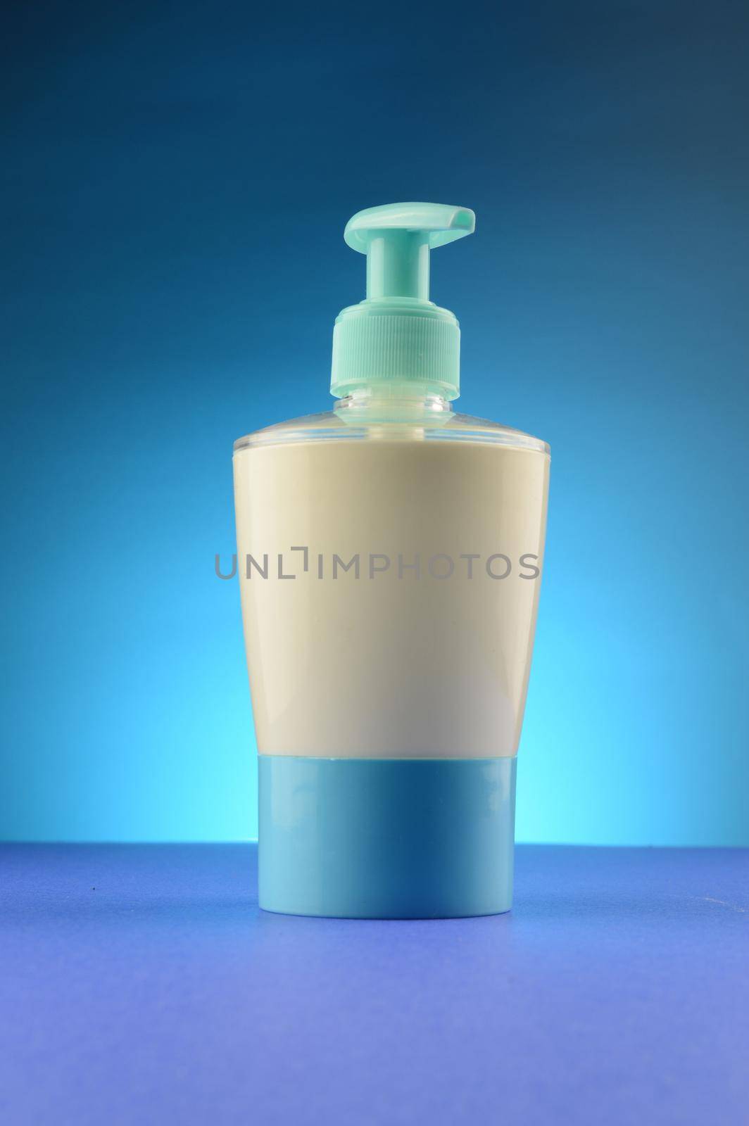 A liquid soap dispenser over a clean blue background.