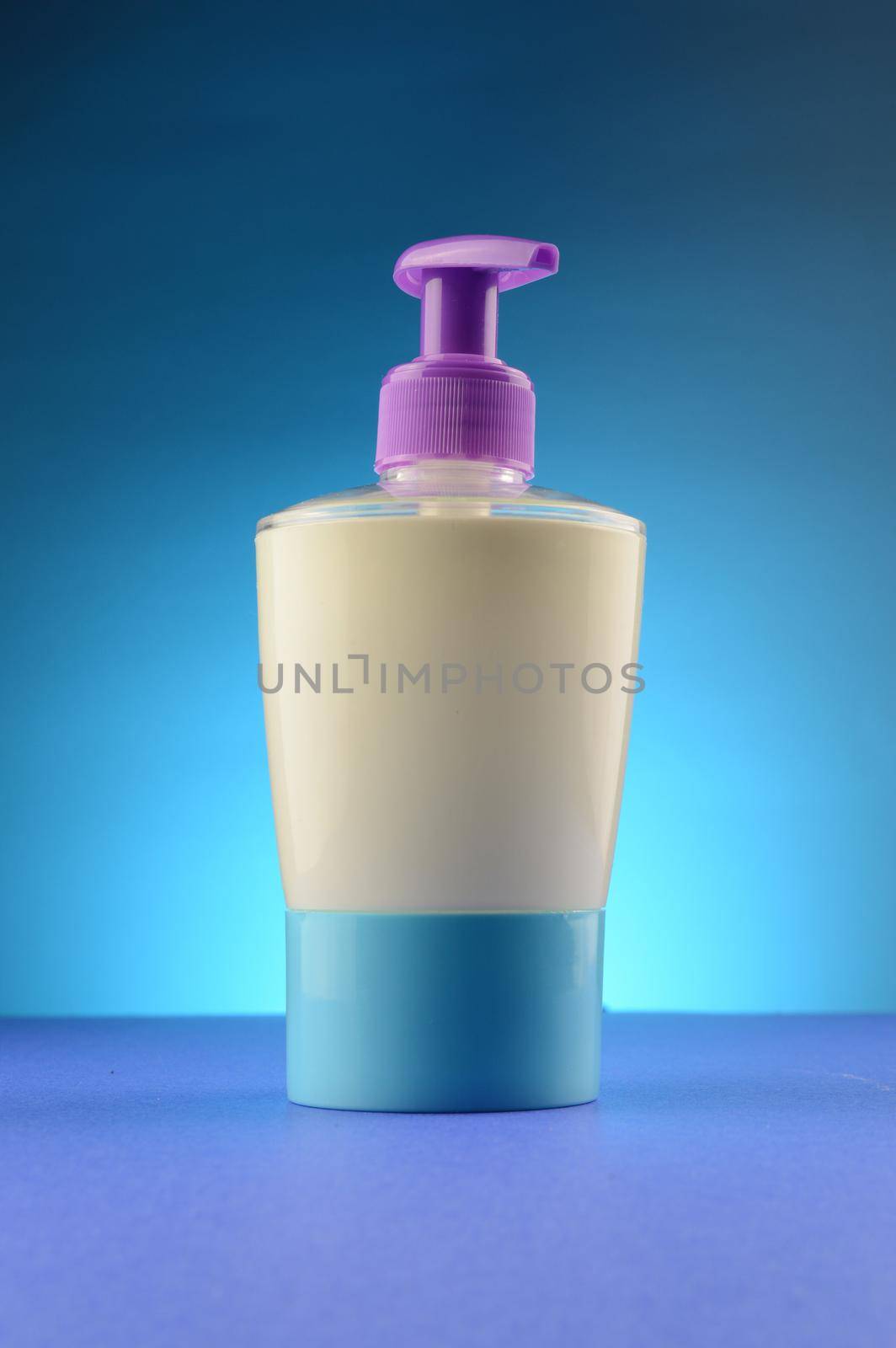 A liquid soap dispenser over a clean blue background.