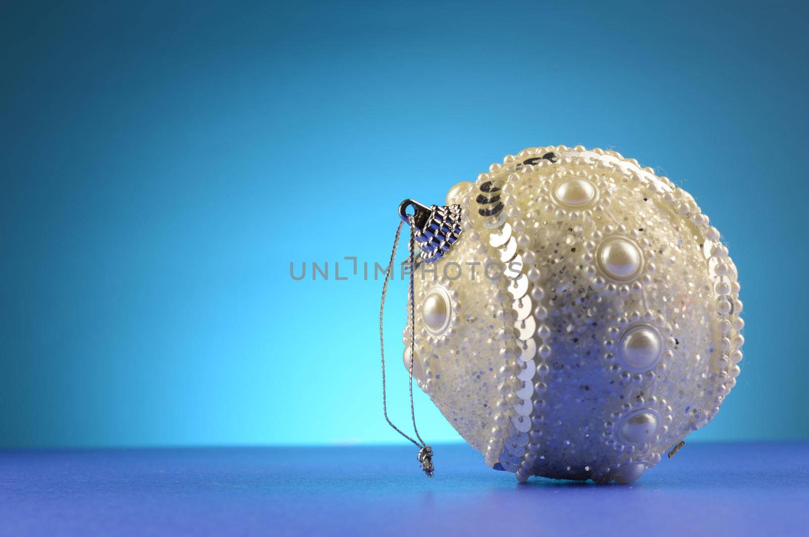 A white Christmas bauble over a cool blue background.