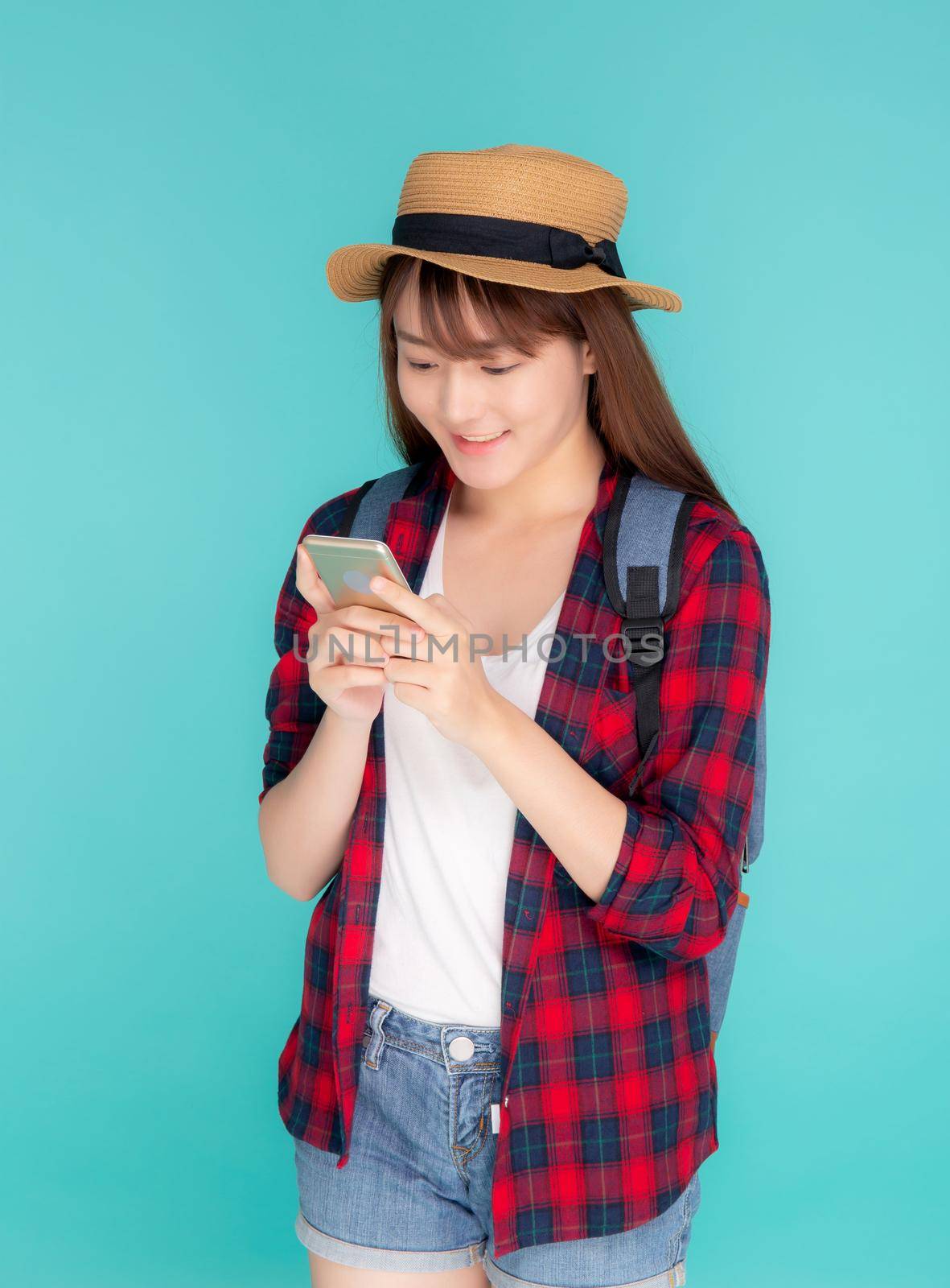 Beautiful young asian woman touch smart mobile phone in vacation isolated on blue background, asia girl talking or chat message on smartphone in travel summer trip, journey or education concept. by nnudoo