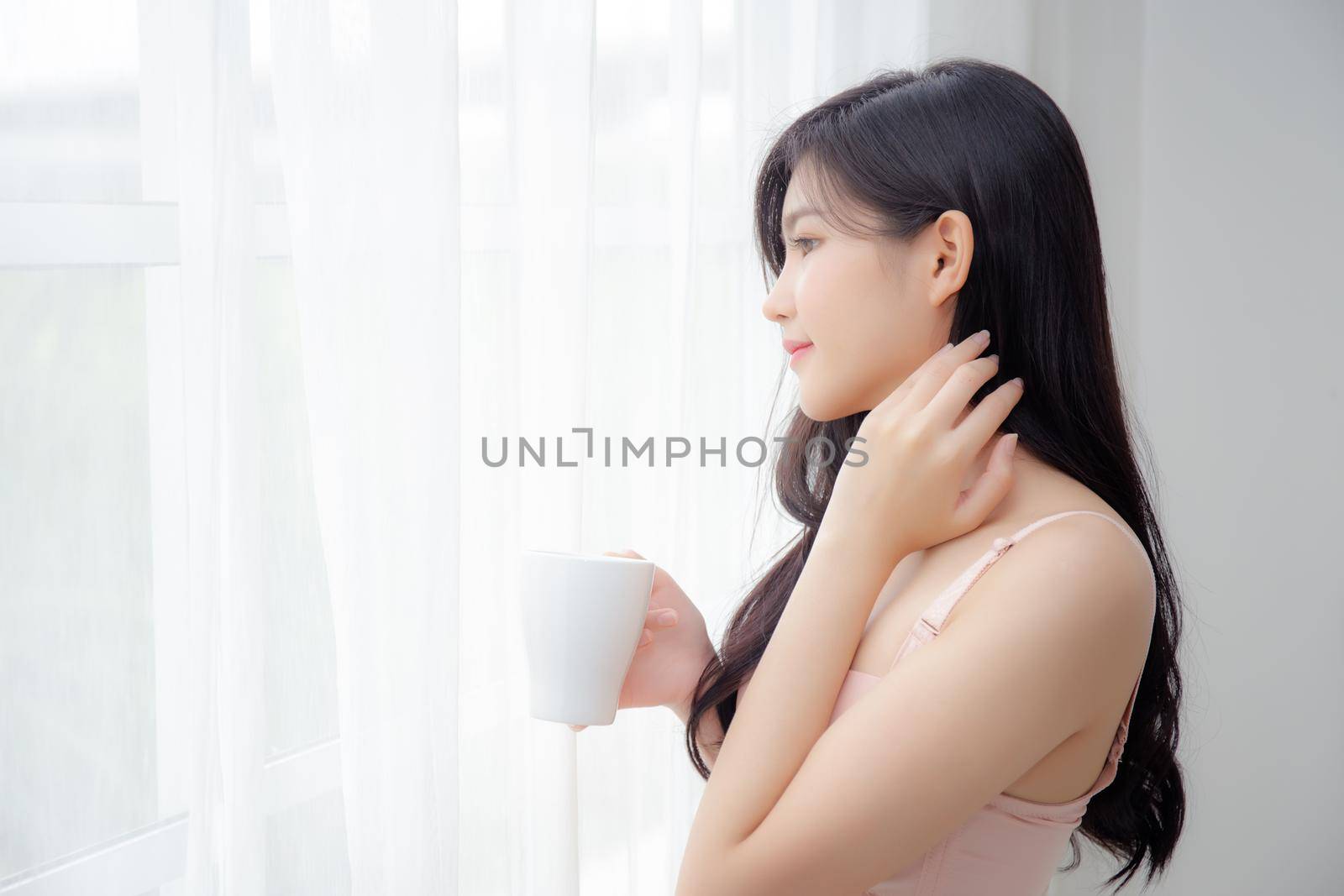 Beautiful young asian sexy woman in underwear drinking coffee near windows in the morning, girl with seductive figure fit drinking beverage for relax and resting after wake up, lifestyle concept.