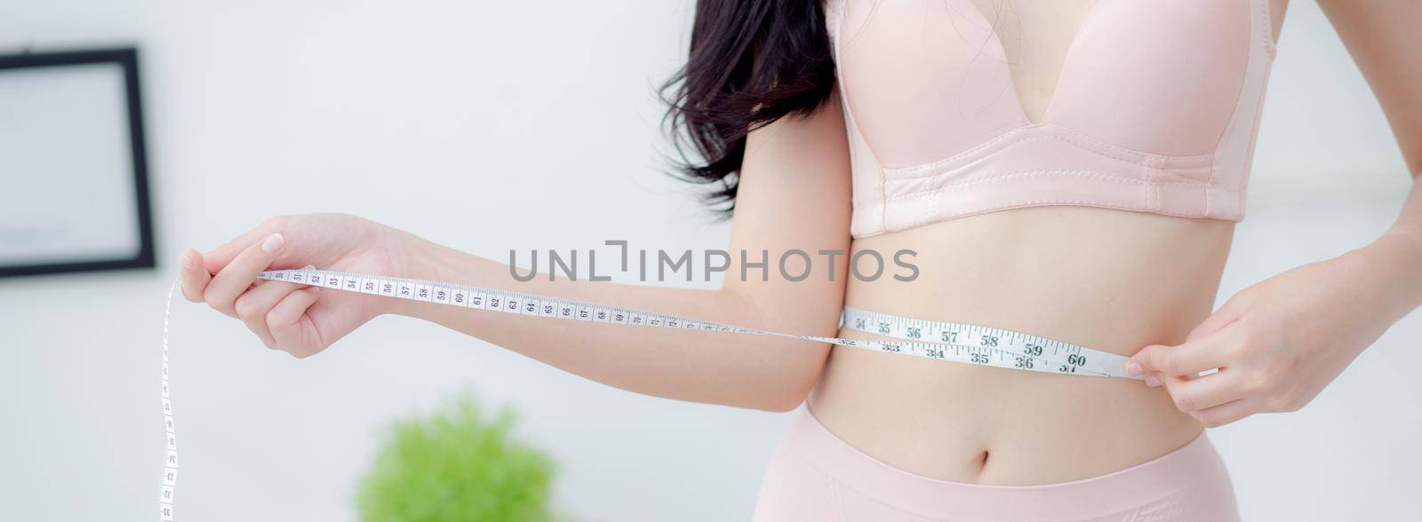 Beautiful young asian woman sexy body slim measuring abdomen for control weight loss in the room, beauty girl belly thin have cellulite with tape measure for diet, health concept, banner website.