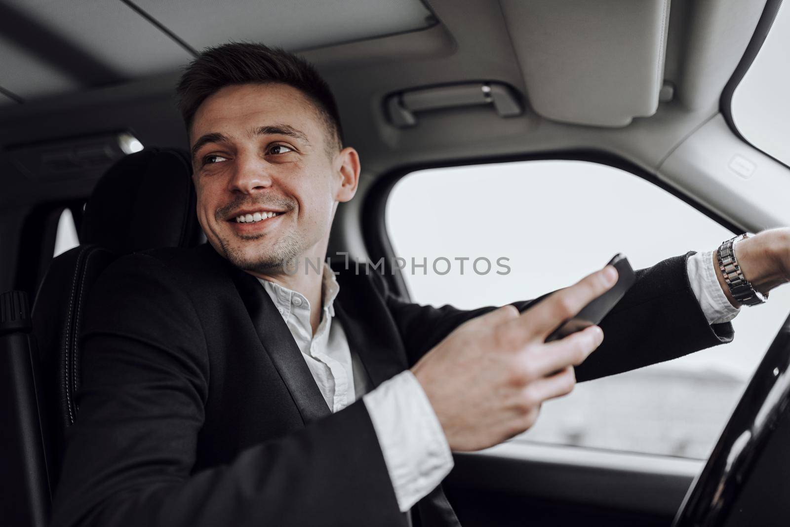 Portrait of smile young businessman holding mobile phone while driving car. Rent and trade-in concept