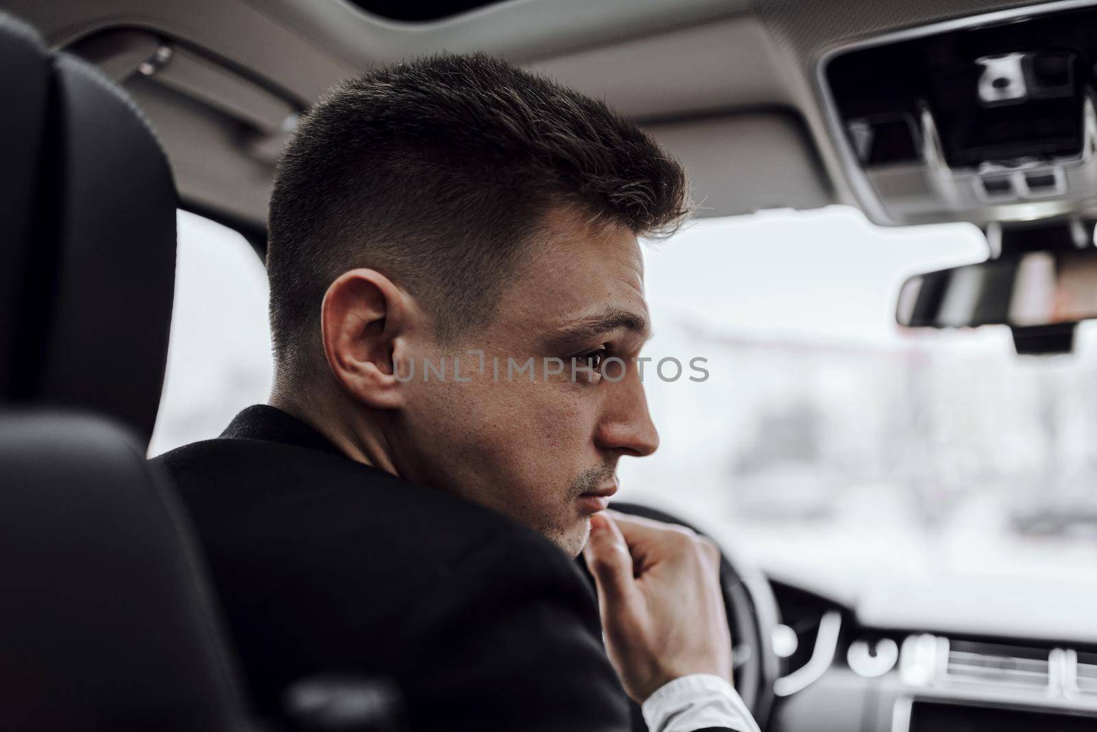 Close up of young man driving in car while renting it. Rent and trade-in concept
