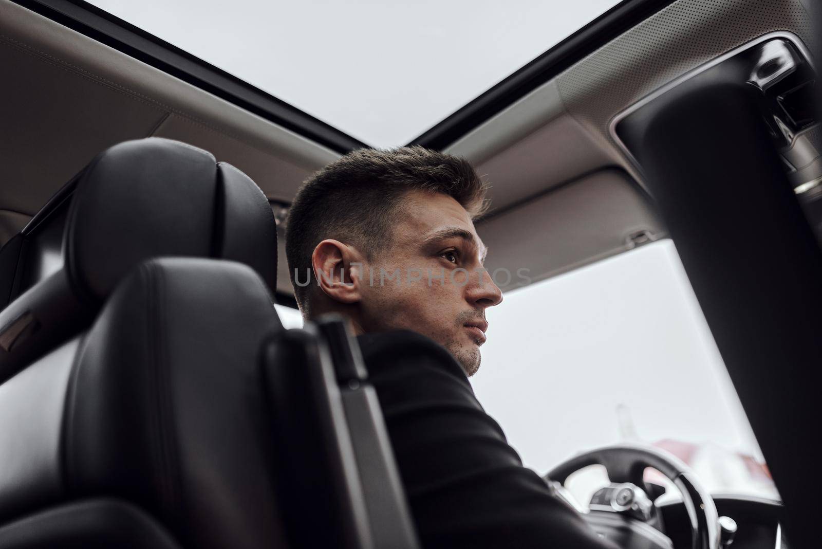 Serious handsome man driving automobile in the city by monakoartstudio