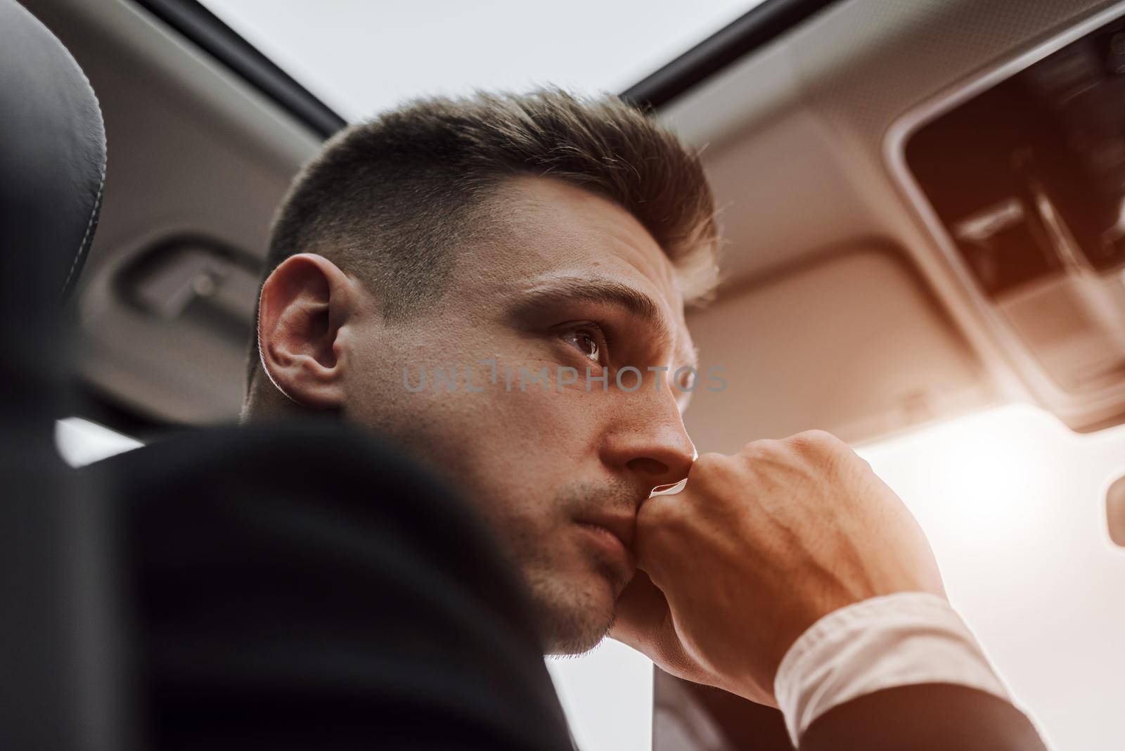 Close up of young man looking away while sitting on seat of car. Rent and trade-in concept