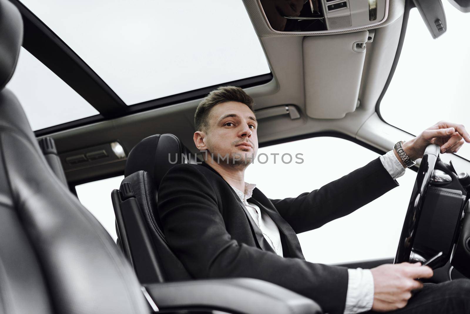 Waist up of confident businessman driving automobile with panoramic roof. Rent and trade-in concept