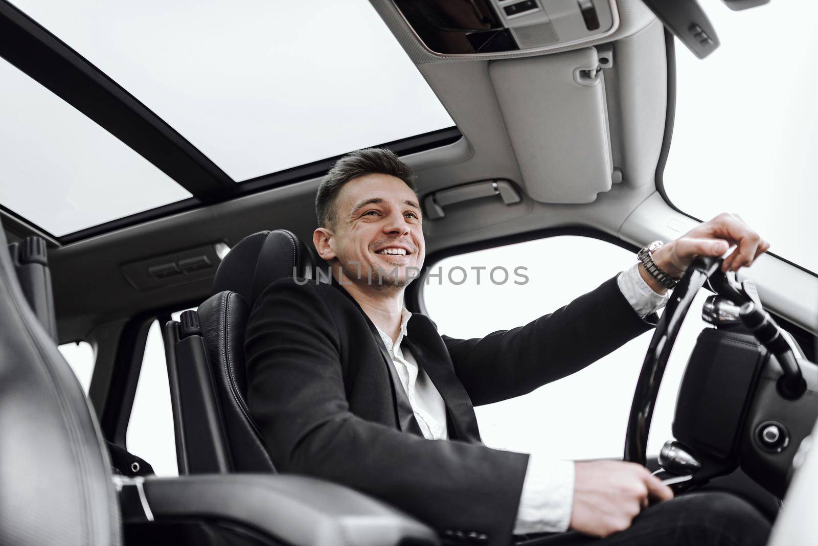 Smiling handsome young man is driving automobile by monakoartstudio