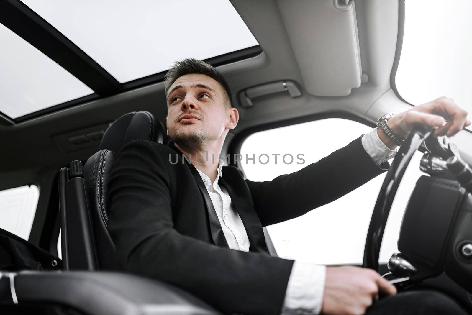 Waist up of male driver riding business class car in the city. Rent and trade-in concept