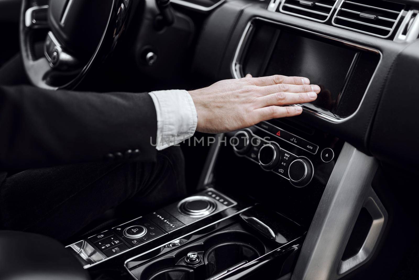 Close up of man turning on stereo system while driving his car. Transportation and vehicle concept