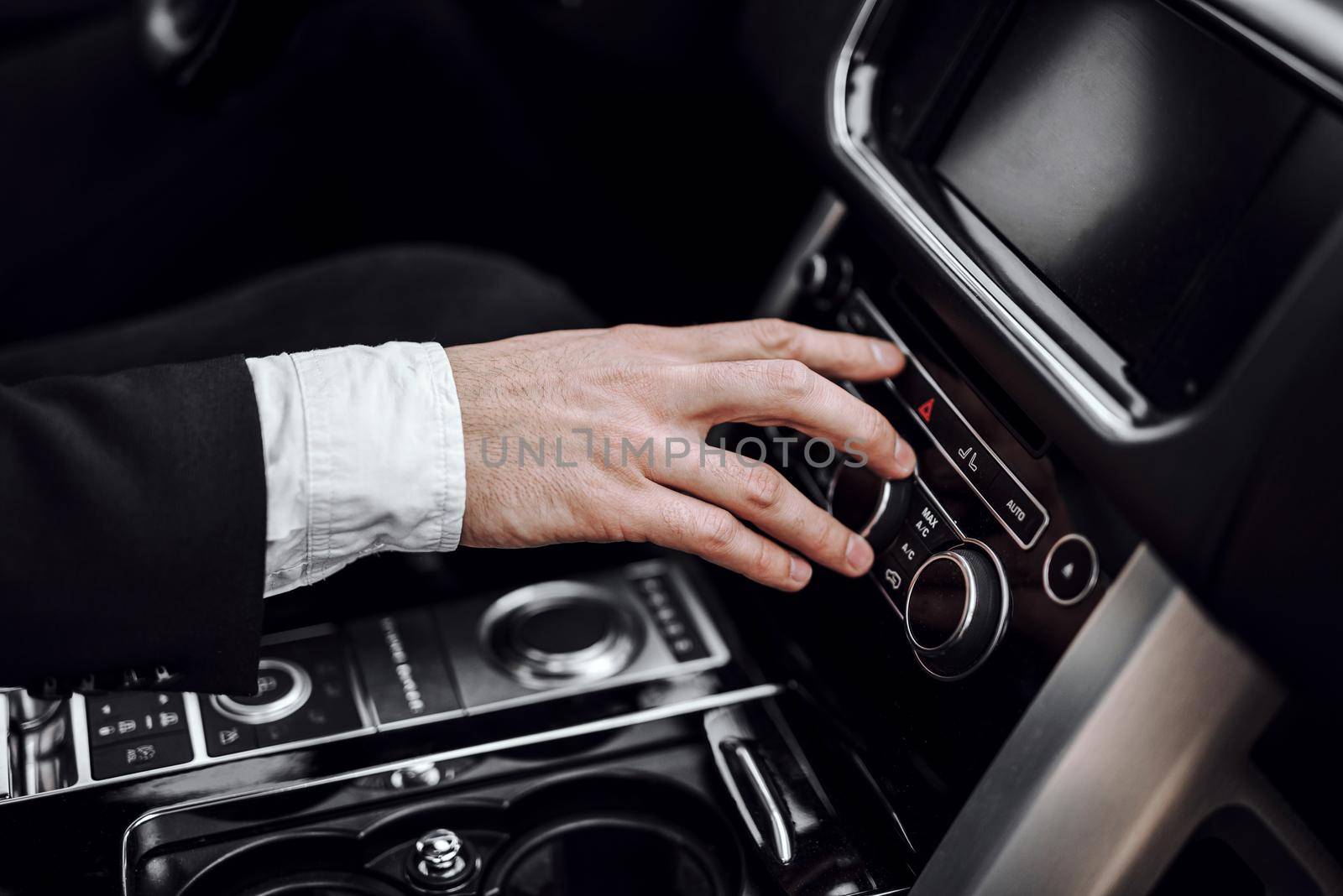 Close up of male hand using audio radio stereo on car panel. Transportation and vehicle concept