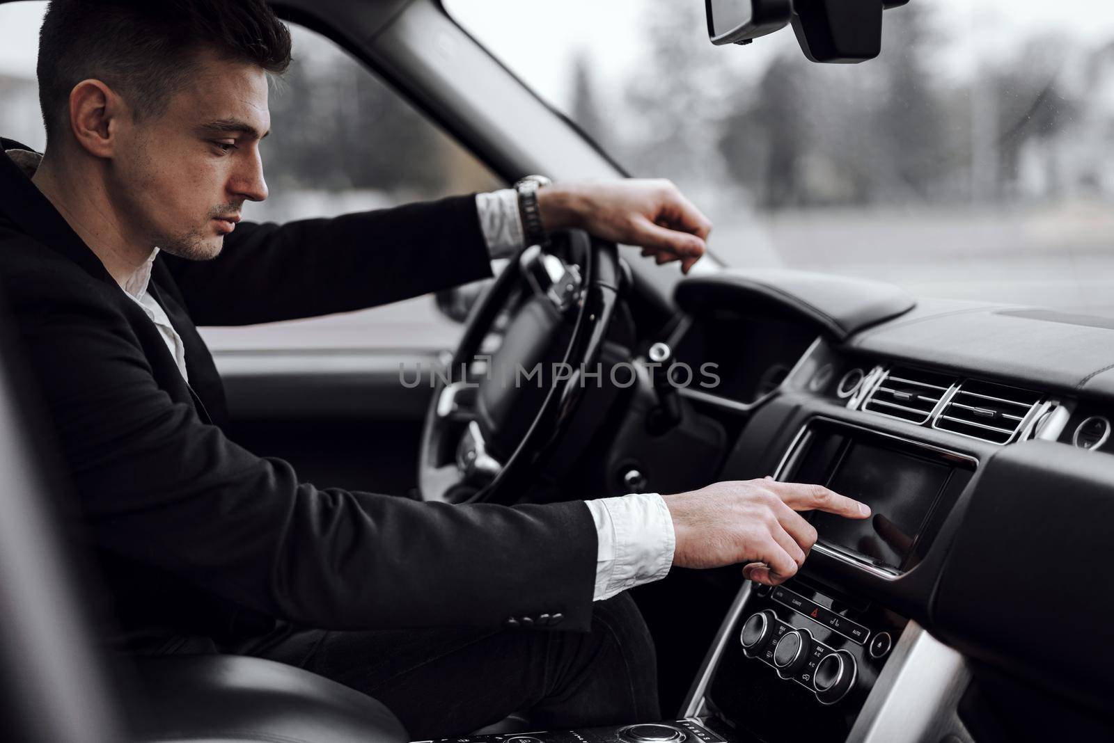 Businessman in jacket sitting in modern automobile by monakoartstudio